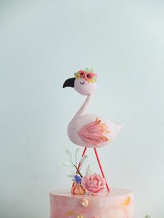 a pink cake with a flamingo on top and flowers in the middle, sitting on a table