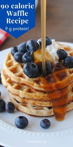 a stack of waffles with syrup and blueberries on the side that is being drizzled