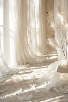 a white room with sheer curtains and a bench in the middle, surrounded by feathers on the floor