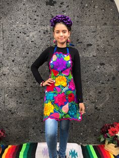 a woman standing in front of a wall wearing an apron and flowered headband