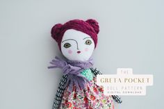 the doll is wearing a dress with flowers on it's body and has a purple scarf around its neck