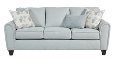 a light blue couch with several pillows on it's arm and back cushions in different colors