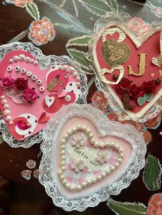 three decorative heart shaped magnets sitting on top of a table