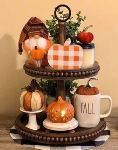 three tiered tray with pumpkins, coffee mugs and other decorative items on it