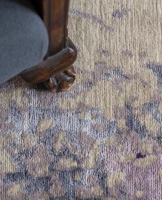 a close up of a rug on the ground with a wooden foot rest in front of it