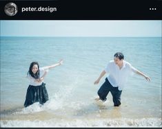 a man and woman are playing in the water at the beach with their arms outstretched