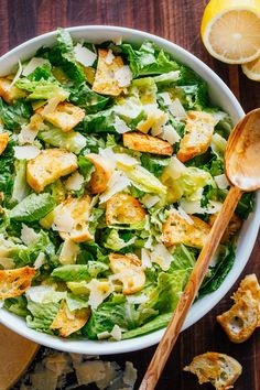 a white bowl filled with salad next to sliced lemons