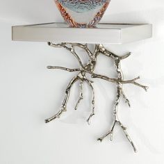 an owl sitting on top of a shelf with branches hanging from it's sides