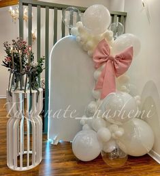 balloons and flowers are on display in front of a white chair with a pink bow