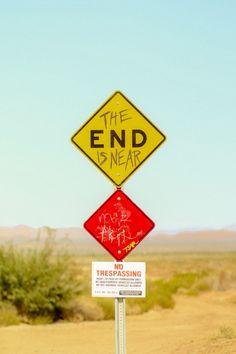 the end is near sign with graffiti on it and another sign that says trespassing