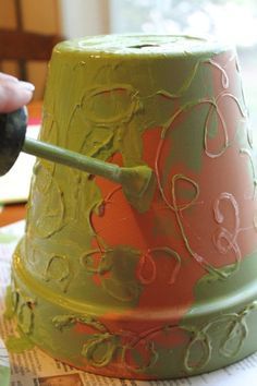 a person is painting a green and red cake with a paintbrush on top of it