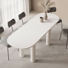 a long white table with four chairs around it and a potted plant in the middle