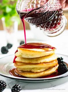 a stack of pancakes with syrup being drizzled over them on a plate