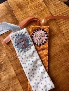 two pieces of fabric on top of a wooden table next to ribbons and tags that say jesus is joy