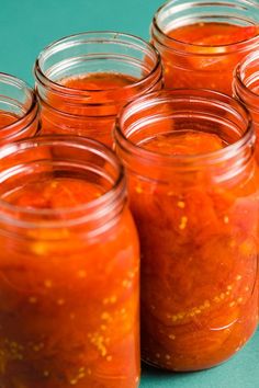 several jars filled with red sauce sitting on top of a blue tablecloth next to each other