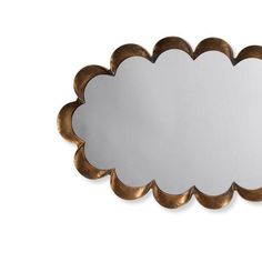 a mirror that is sitting on top of a white wall with a gold frame and scalloped edge