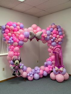 the balloon arch is decorated with minnie mouses and pink, purple, and white balloons