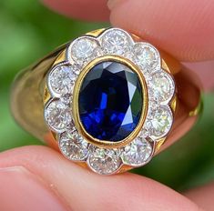 a close up of a person's hand holding a ring with a blue stone