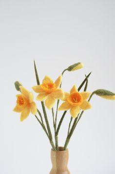 three yellow flowers are in a small vase