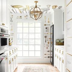 a kitchen with white cabinets and gold accents on the ceiling, along with a chandelier