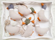 four stuffed ducks in a white box on a furnishing area with rope and pom poms