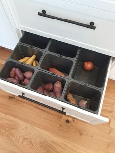 an open drawer filled with different types of vegetables and fruits in containers on top of a wooden floor