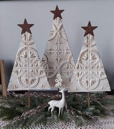 three wooden christmas trees on top of a table next to a deer figurine