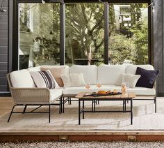 an outdoor living room with white furniture and large windows