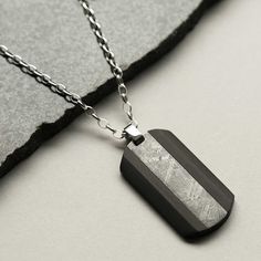 Our Meteorite and Carbon Fibre Dog Tag Necklace is a little piece of outer space you can wear on the daily. An out-of-this-world gift for the ones in your life who loves space. This dog tag necklace is styled with carbon fibre for a modern take on meteorite jewellery. Over 100,000 years ago, a handful of these mysterious Muonionalusta meteorites impacted earth. Searches for the impact crater from the original shower have been in vain; the site where these specimens are found is in a remote area of northern Sweden, is it presumed they were carried there by glaciers. Our Meteorite and Carbon Fibre Dog Tag Necklace comes in a elegant textured presentation box complete with information card and certificate of authenticity. The meteorites are not only extremely rare, they are almost always buri Minimalist Stainless Steel Dog Tag Necklace, Black Stainless Steel Jewelry For Everyday Use, Everyday Black Stainless Steel Jewelry, Nickel-free Stainless Steel Dog Tag, Engraved Pendant Necklaces, Adjustable Dog Tag Jewelry Gift, Adjustable Dog Tag Jewelry For Gift, Hypoallergenic Dog Tag Jewelry For Gift, Everyday Metal Dog Tag Necklace