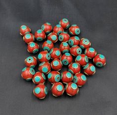 several red and turquoise beads on a black surface