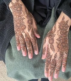 a woman's hands with henna tattoos on her arm and hand, showing the intricate