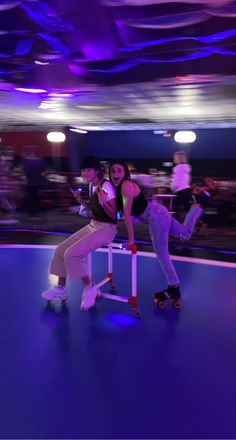 two people on roller skates in an indoor area with purple lights and blue lighting