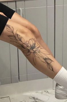 a woman's leg with flowers on it and white socks in a bathroom area