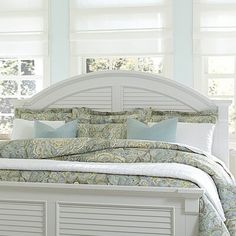 a white bed with blue and green pillows