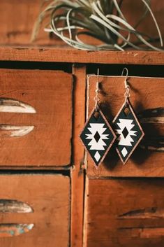 two black and white earrings hanging from wooden drawers