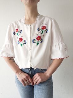 Beautiful white handmade blouse with lace at the neck, flared puff sleeves and stunning embroidery flowers. Size and fabric unknown, most likely cotton-polyester blend. The blouse will fit size S (on a pictures) up to L/XL. Measurement, single flat lying: Shoulders 42 cm Chest 54 cm Length 59 cm Vintage White Peasant Top With Puff Sleeves, Vintage Cotton Peasant Top For Spring, White Vintage Peasant Top For Spring, Cotton Embroidered Puff Sleeve Blouse, Vintage White Floral Print Blouse, Vintage Peasant Top With Floral Print For Spring, Vintage White Blouse With Floral Print, Spring Vintage Peasant Top With Floral Print, White Puff Sleeve Blouse With Floral Embroidery