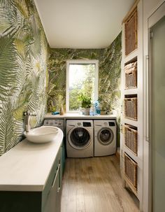 a washer and dryer in a small room with tropical wallpaper on the walls