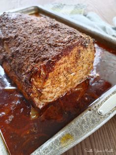 a piece of meat sitting on top of a pan covered in sauce