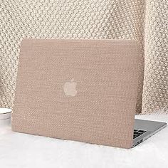 an apple laptop sitting on top of a white blanket next to a cup of coffee