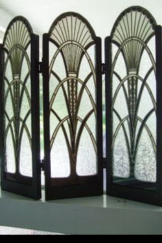 three decorative screens sitting on top of a table next to a window with glass panels