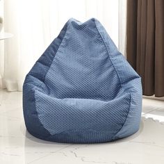 a blue bean bag chair sitting on top of a white tile floor next to a window