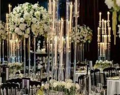 the centerpieces in this wedding reception are tall, clear vases with white flowers and candles