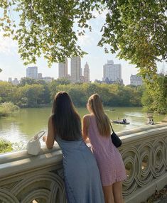 two girls looking out over the water from a bridge in central park, new york city