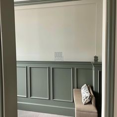 an empty room with green paneling on the walls and a bench in the middle