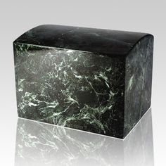 a green marble block sitting on top of a white surface with a reflection in it