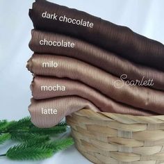 a basket filled with lots of different types of fabric next to green leaves and pine branches