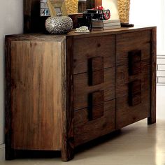 a wooden dresser sitting next to a mirror on top of a white wall in a room