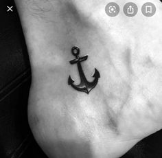 a small anchor tattoo on the side of a woman's foot with butterflies around it