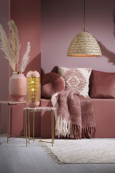 a living room with pink walls and pillows on the couch, rugs and tables