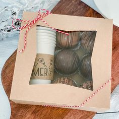 a box filled with chocolate covered donuts on top of a wooden cutting board next to a cup